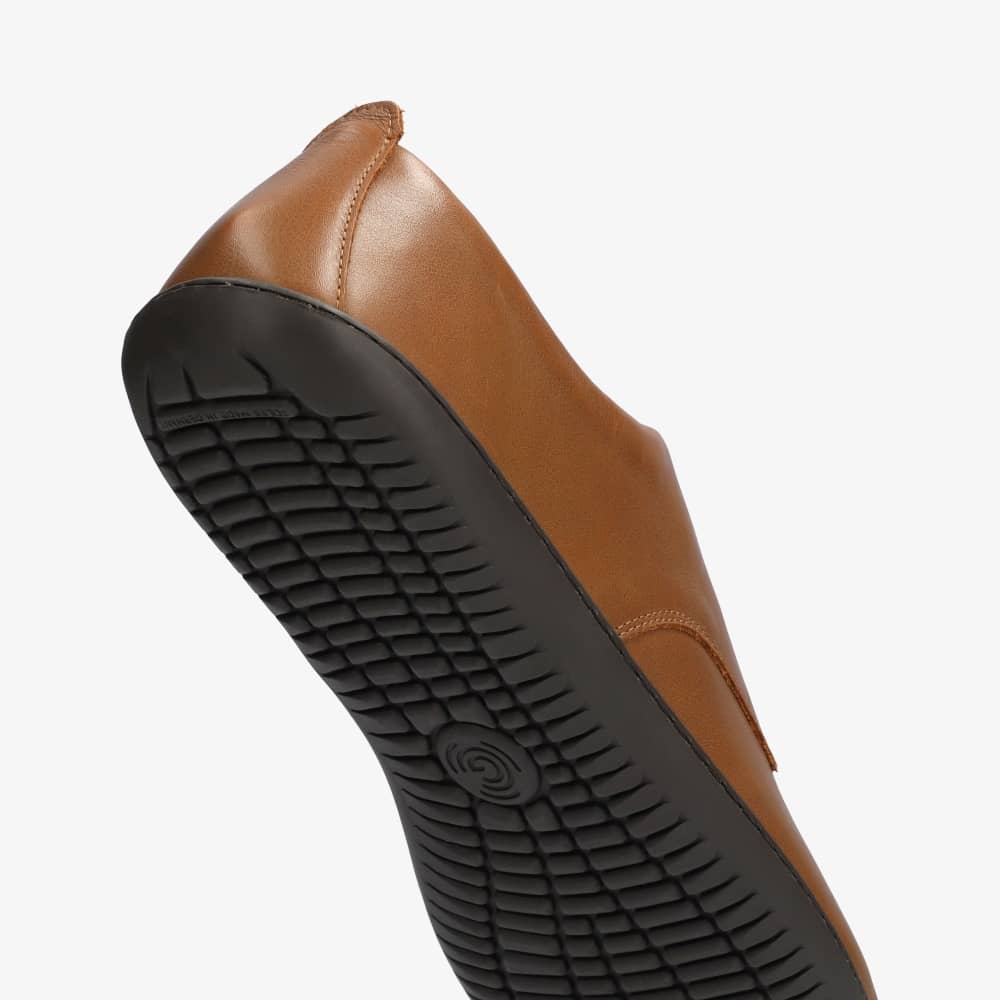 A photo of Groundies Palermo dress shoes made of leather upper and rubber soles. The shoes are a brown color with black soles and dress sole detailing by the laces. The left shoe is shown from below against a white background with a focus on the bumpy rubber sole. #color_brown