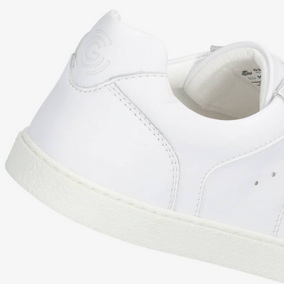 A photo of white Groundies Universe sneakers made of leather with classic sneaker details. A close up shown floating from the right back heel against a white background in this photo. #color_white