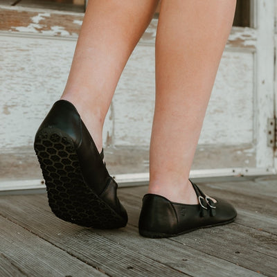 Black leather Villet Mary Jane flats with double straps with silver buckle closures, tan leather lining, and black rubber soles. #color_black-smooth