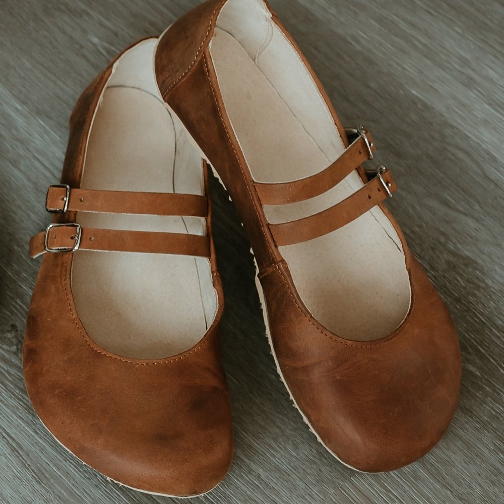 Brown leather Villet Mary Jane flats with double straps with silver buckle closures, tan leather lining, and beige rubber soles. #color_brown-nubuck