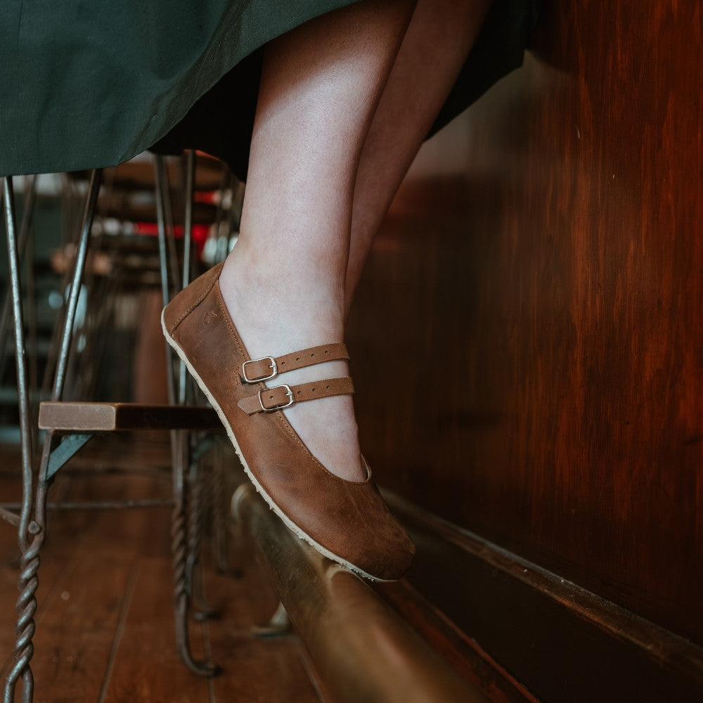 Brown leather Villet Mary Jane flats with double straps with silver buckle closures, tan leather lining, and beige rubber soles. #color_brown-nubuck