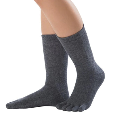 A pair of charcoal Knitido crew-cut cotton & merino toe socks. Both socks are shown facing diagonally left against a white background on a person with the left heel up. #color_charcoal