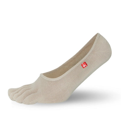 A photo of Knitido track and trail footies socks made with cotton, nylon, polyester, and elastane. The socks are a beige color. One sock is shown facing to the left with the heel lifted slightly off the floor against a white background. #color_beige