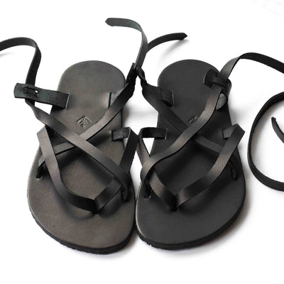 A black leather strappy sandal shown from the front on a white background. #color_black