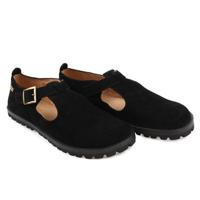 A black, suede t-bar flat with tan lining, a gold buckle, thick black soles, and a small pull tab in the back. Both shoes are shown facing diagonally right against a white background. #color_black