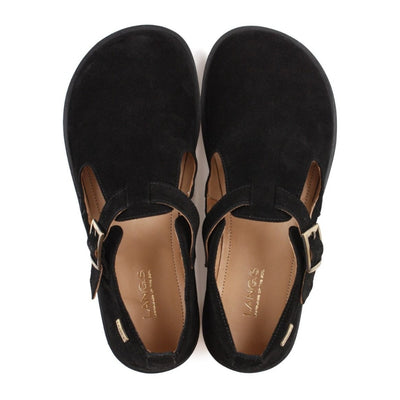 A black, suede t-bar flat with tan lining, a gold buckle, thick black soles, and a small pull tab in the back. Both shoes are shown from above against a white background. #color_black