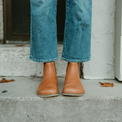 Brown leather Lang.S Luna Chelsea boots with a pull tab, tan interior leather, and tan rubber. Both boots are shown from the front woman wearing medium wash, loose, cropped jeans standing on cement stairs. #color_brown