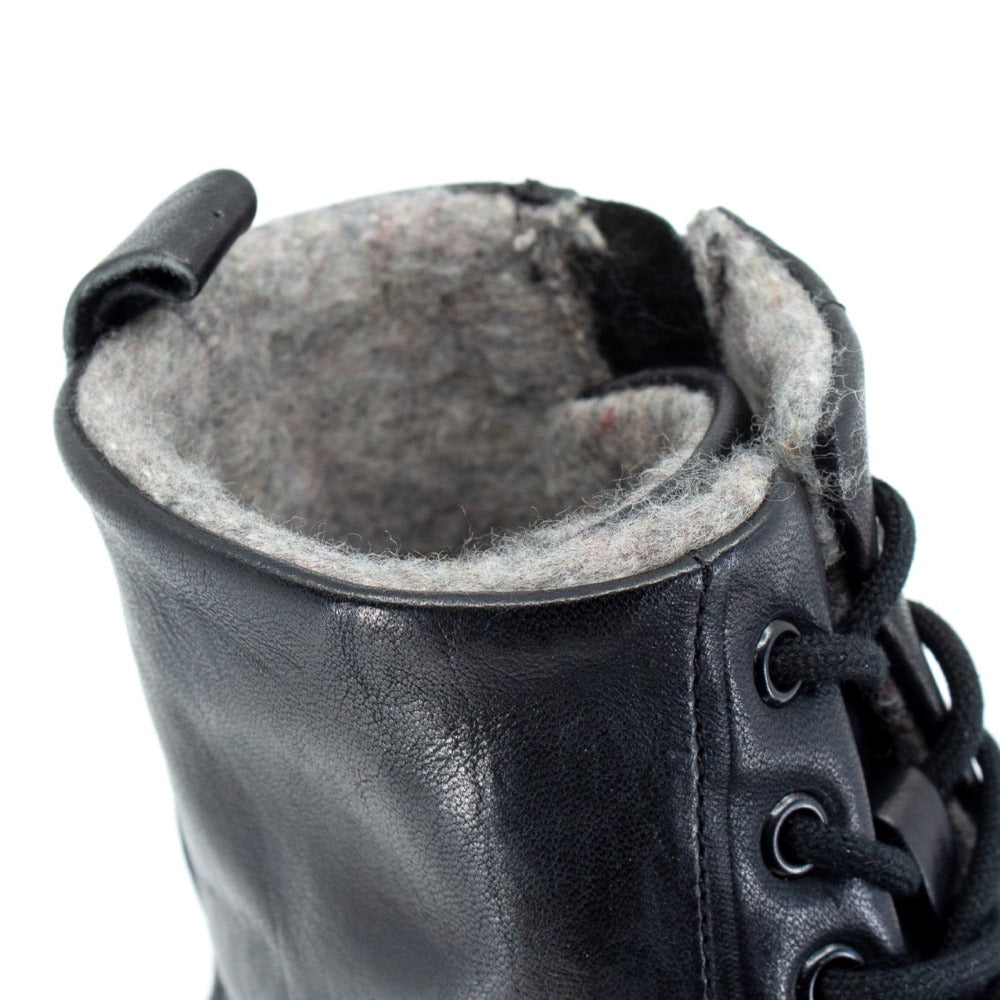 Black, leather, wool-lined Mukishoes Igneous combat-style, zip-up boots. Right shoe opening is shown close-up here facing diagonally right against a white background. #color_black