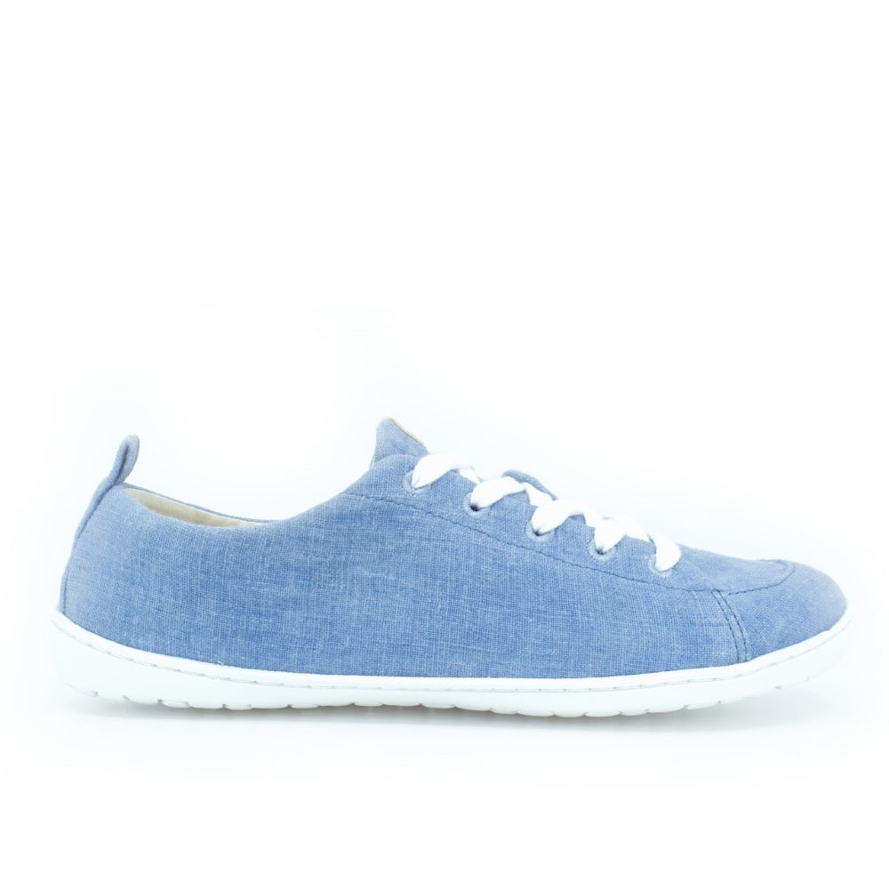 A photo of Mukishoes Indigo fabric sneakers. Shoes are simple in design, have a pull tab on the back, and white lining, laces, and soles. Right shoe is shown here facing to the right against a white background. #color_indigo