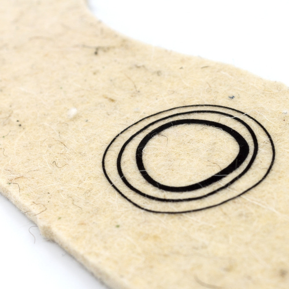 One cream wool and hemp fiber Mukishoes insoles shown close up on the heel logo detail against a white background.