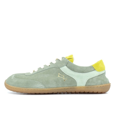 Theia (multiple green colors) Mukishoes Lyra suede leather sneakers with, white laces, and a natural rubber colored sole. Shoes are all sage green colored with a T-shaped detail on the toe box in sage green, a T-shaped seafoam green detail on both sides of the ankle, and neon green color detail on the top of the tongue and heel. Left shoe is shown here facing left against a white background. #color_theia