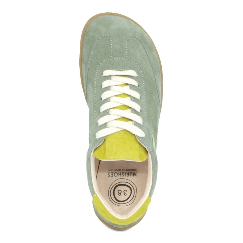 Theia (multiple green colors) Mukishoes Lyra suede leather sneakers with, white laces, and a natural rubber colored sole. Shoes are all sage green colored with a T-shaped detail on the toe box in sage green, a T-shaped seafoam green detail on both sides of the ankle, and neon green color detail on the top of the tongue and heel. Right shoe is shown from above against a white background. #color_theia