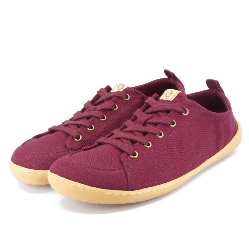 A photo of Mukishoes Roma fabric sneakers. Shoes are a deep wine color, simple in design, have a pull tab on the back, and a deep-wine colored lining, laces, and gum colored soles. Both shoes are shown diagonally here facing slightly to the left against a white background. #color_roma