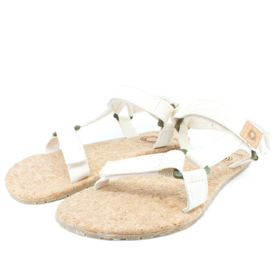 Cream Mukishoes Solstice. Sandals have thicker cotton adjustable straps going over the toes and surrounding the ankle with straps connecting the toe and ankle straps. Footbed is quark and sole is a thin tan rubber. Both shoes are shown here diagonally facing to the left against a white background. #color_natural-cream