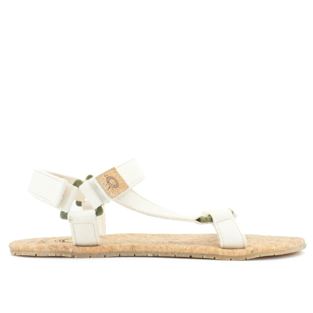 Cream Mukishoes Solstice. Sandals have thicker cotton adjustable straps going over the toes and surrounding the ankle with straps connecting the toe and ankle straps. Footbed is quark and sole is a thin tan rubber. Right shoe is shown here facing to the right against a white background. #color_natural-cream