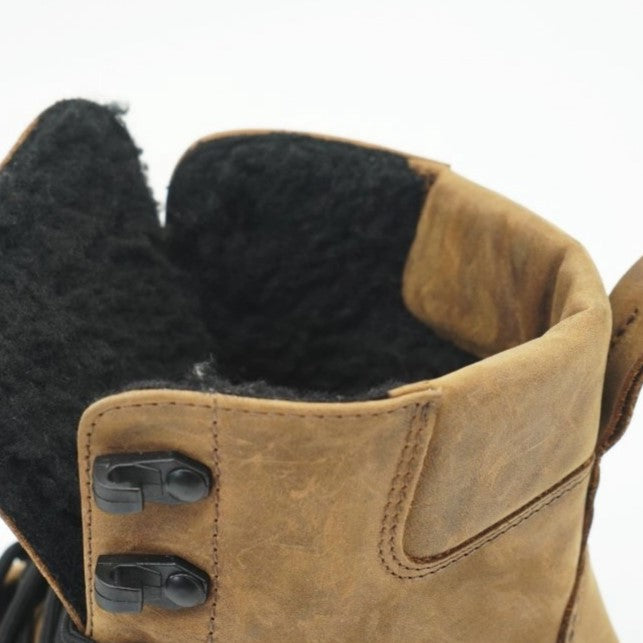 Light Brown shearling-lined leather Realfoot Farmer Winter boots with black laces, eyelets, and soles. Boots go over the ankle with padding and a pull tab in the back and a longer tongue. Two quick lace hooks are at the top of the laces and soles are stitched and glued. Left boot opening and lining is shown close up facing left against a white background. #color_light-brown