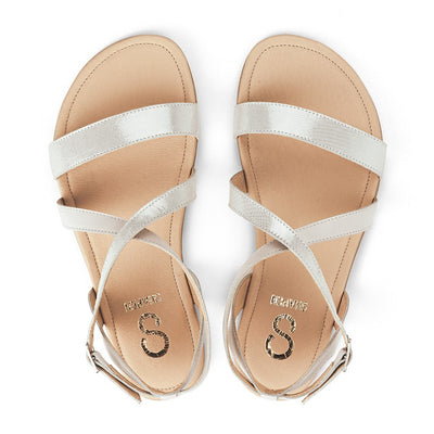 A photo of White Shapen Calla Sandals made with leather and tan rubber soles. The sandals have a slight sparkle. Both sandals are shown from the top down against a white background in this photo. #color_white