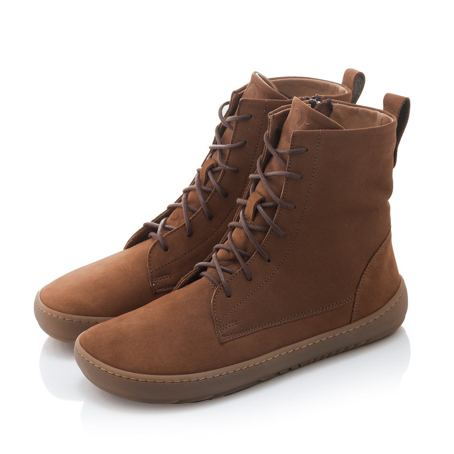 A photo of the Shapen Cozy lace up boots made from a water resistant nubuck leather upper, wool lining, and brown rubber soles. The boots are brown in color with brown laces and have a zipper on the inner side. Both boots are shown diagonally from the left side against a white background.
#color_brown