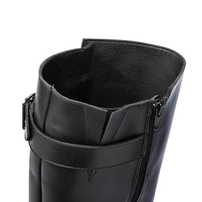 A photo of Shapen Glam lined riding boots made with leather, a faux fur lining, and rubber soles. The boots are black in color with zippers on the side and silver buckles on the top and around the ankle, the ankle buckle strap is removable. Am up close shot is shown off the top of the boots to show the detail against a white background. #color_black