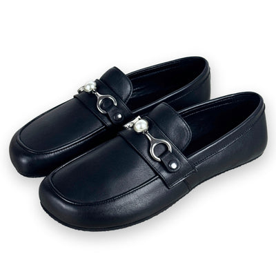 A silver metal accessory for the Shapen Versa Loafer. Chain is attached by a D shape on either side that tapers into holding a pearl detail in the middle. Accessory is shown on black Shapen Versa Loafers facing diagonally left against a white background. #color_gold-chain
