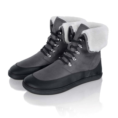 A photo of the Shapen Lynx lace up boots made from a water-resistant nubuck leather uppers and black rubber soles. The boots are dark grey in color, have a black leather rim around the bottom inch of the shoe, black laces, and a white wool lining that can be shown by folding over the top of the boots. Both boots are shown together from the front left side with the top of the boots folded down on a white background. #color_dark-grey
