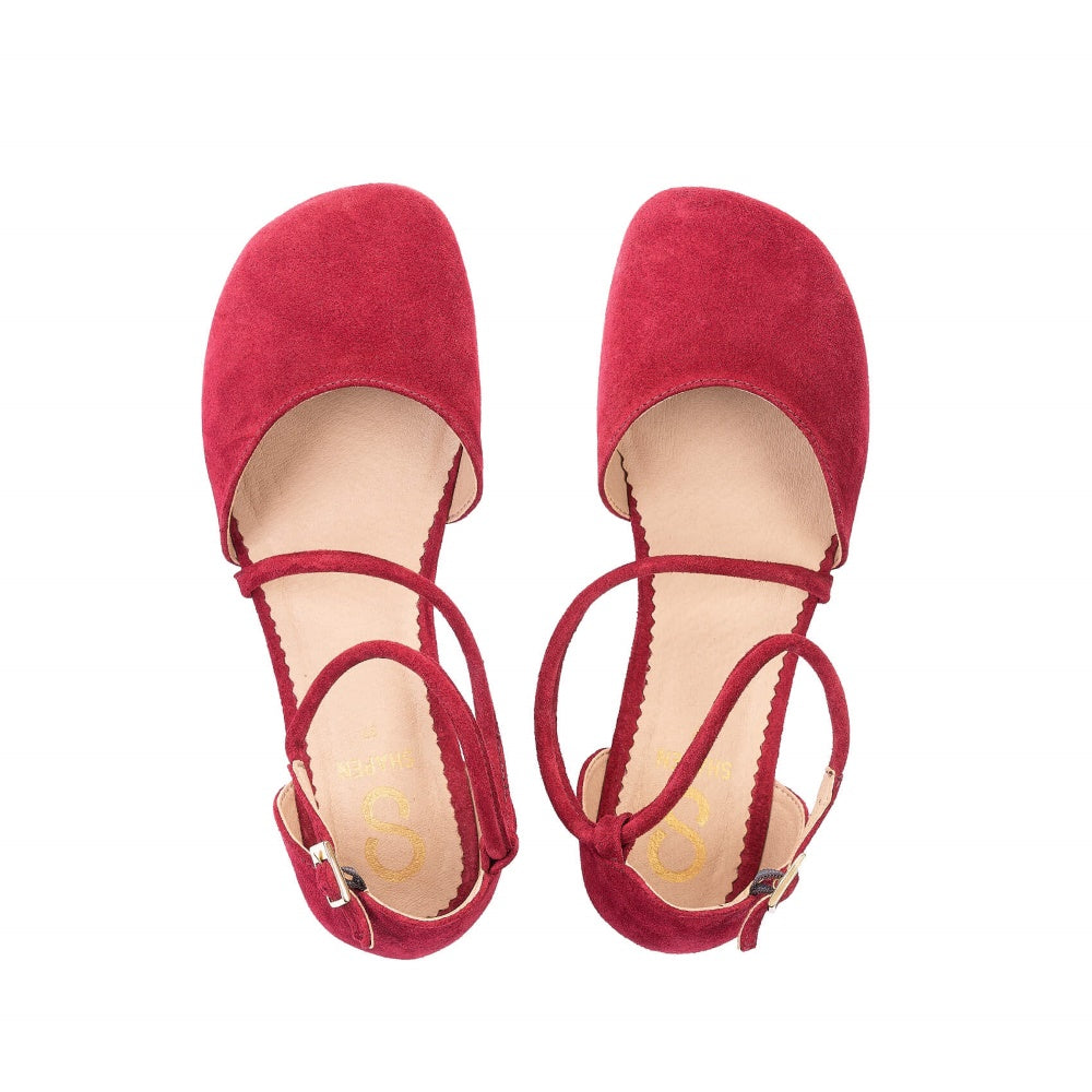 A photo of dark red Shapen Orchid flats.  Shoes are suede with tan rubber soles. A toe box and heel cup bookmark each end of the shoe with a round strap that zig zags from the toe box to the ankle/heel cup to keep the shoes secured to the foot. Both shoes are shown here from above against a white background. #color_bordeaux