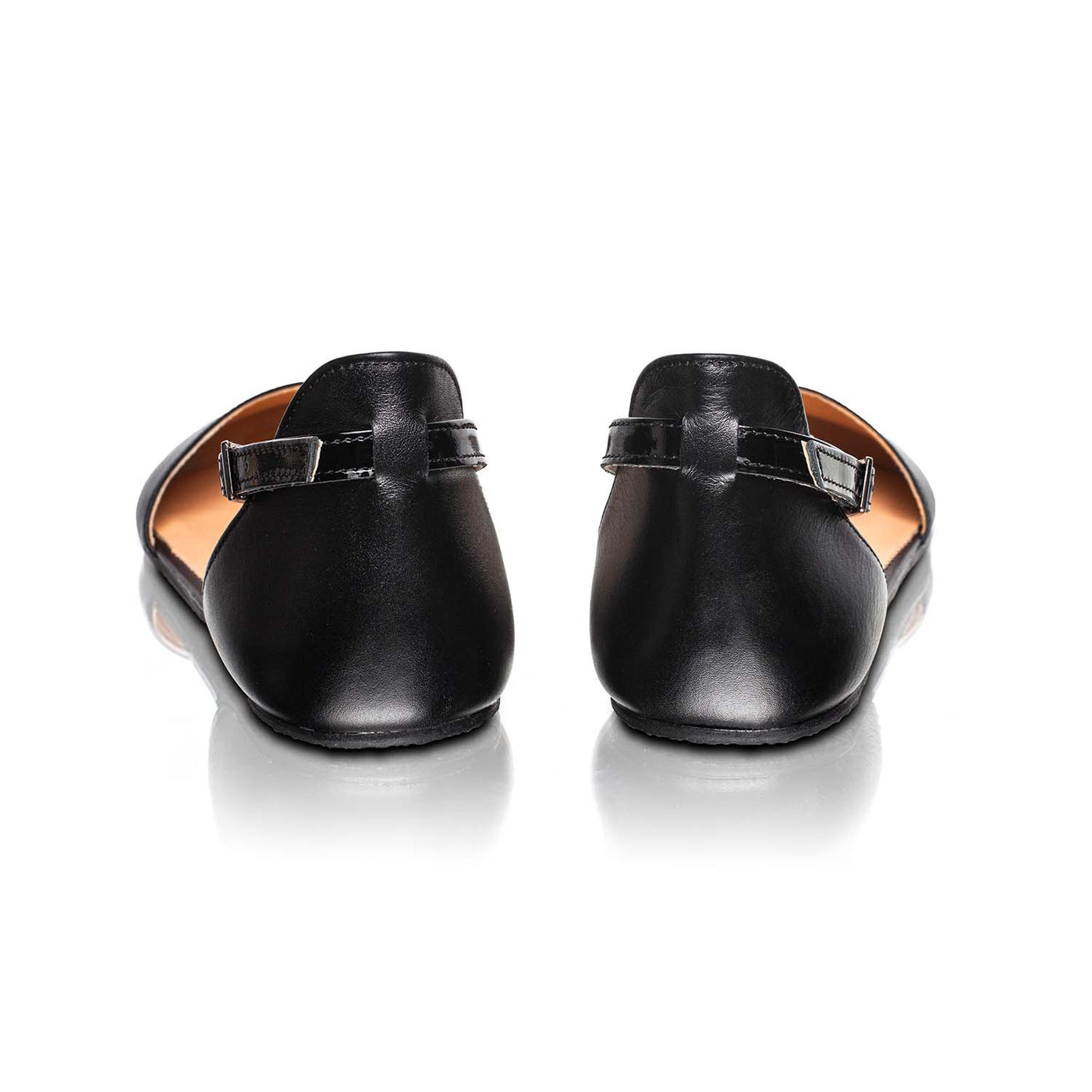A photo of Shapen Poppy D’orsay dressy flats with a leather upper and rubber soles. The flats are a black color with a heel cup and dainty ankle strap, the inside of the sole are a beige color. Both flats are shown from the back against a white background. #color_black