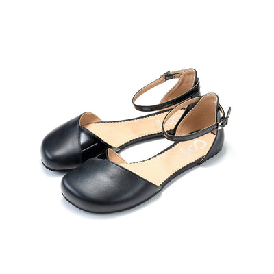 Black leather Shapen Poppy D’orsay dressy flats with a tan footbed and tan rubber soles. The flats have a heel cup held on by a dainty, patent leather ankle strap. Both flats are shown facing diagonally left against a white background. #color_black
