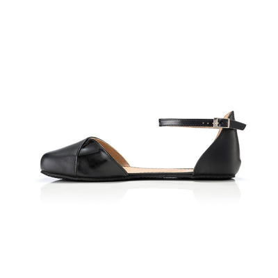 Black leather Shapen Poppy D’orsay dressy flats with a an footbed and tan rubber soles. The flats have a heel cup held on by a dainty , patent leather ankle strap. Right flat is shown facing left against a white background. #color_black