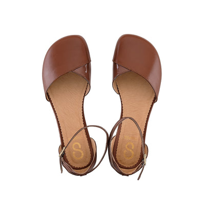A photo of Shapen Poppy D’orsay dressy flats with a leather upper and rubber soles. The flats are a cognac brown color with a heel cup and dainty ankle strap, the inside of the sole are a beige color. Both flats are shown here from the top down against a white background. #color_cognac