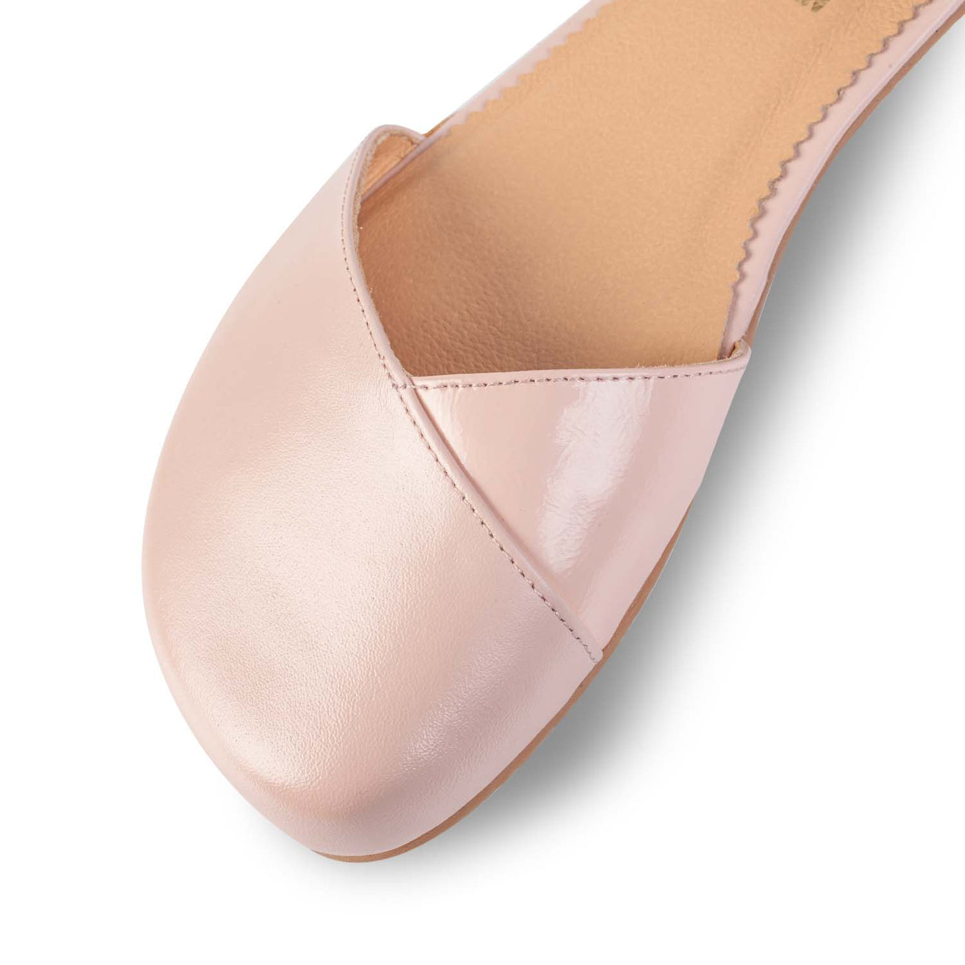 A photo of Shapen Poppy D’orsay dressy flats with a leather upper and rubber soles. The flats are a rose beige color with a heel cup and dainty ankle strap, the inside of the sole are a beige color. The right shoe is shown up close from the front against a white background. #color_rose