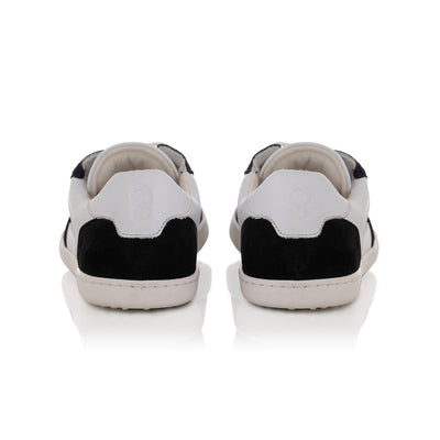 A photo of Shapen ReWind leather sneakers in white & black. Shoes are a classic chunky sneaker design with black suede color blocks surrounding the toe guard, laces, and heels. Both shoes are shown here from the back against a white background. #color_black-white