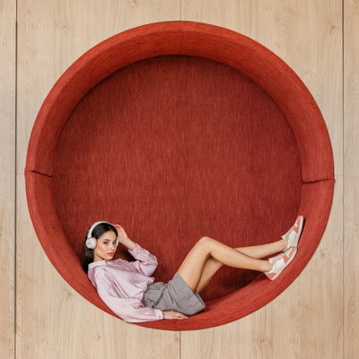 Peach Shapen ReWind leather sneakers. Shoes are a classic chunky sneaker design with light pink leather and peach suede color blocks surrounding the toe guard and heels. Light grey suede color blocks are on the perimeter of the laces and the top of the heel. Both shoes are shown staggered facing right on a woman laying back in a red circular bench set inside a wall. She is wearing headphones and a pink satin long sleeve dress shirt tucked into loose, grey dress shorts.  #color_peach