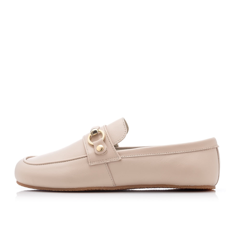 Beige leather Shapen Versa loafers. Shoes are a classic loafer design with a leather decoration capped by gold metal rings across the foot and tan rubber soles glued on. Left shoe is shown facing left against a white background. #color_beige