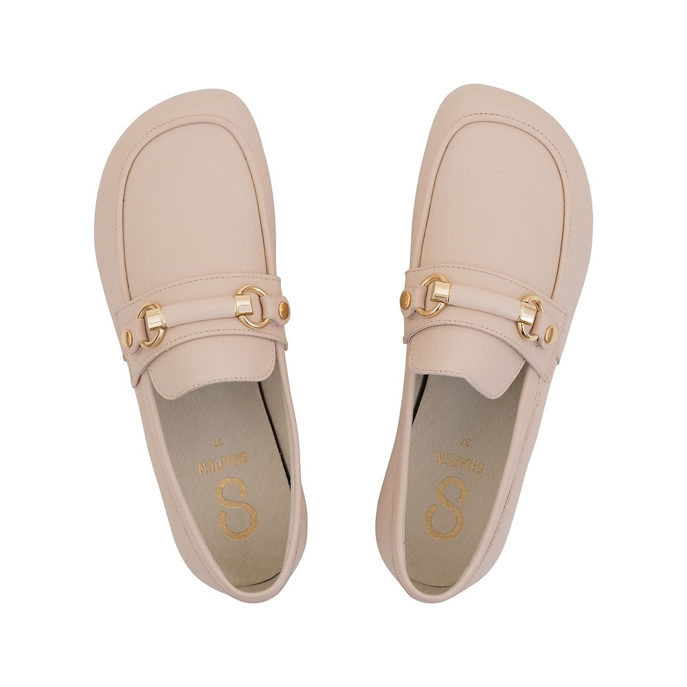 Beige leather Shapen Versa loafers. Shoes are a classic loafer design with a leather decoration capped by gold metal rings across the foot and tan rubber soles glued on. Both shoes are shown from above against a white background. #color_beige