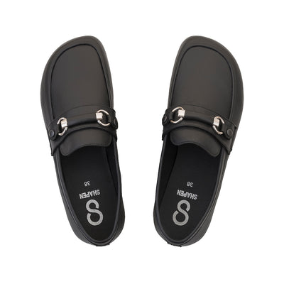 Black leather Shapen Versa loafers. Shoes are a classic loafer design with a leather decoration capped by silver metal rings across the foot and black rubber soles glued on. Both shoes are shown from above against a white background. #color_black