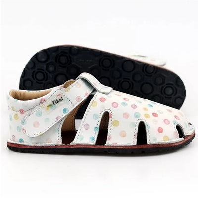 A photo of Tikki Aranya kids sandals in Confetti. Sandals are surrounded in leather with 4 slits on each side and a velcro closure across the foot. Footbed is brown and soles are black. Right shoe is shown here facing right with the left shoe sole facing left behind it against a white background. #color_confetti