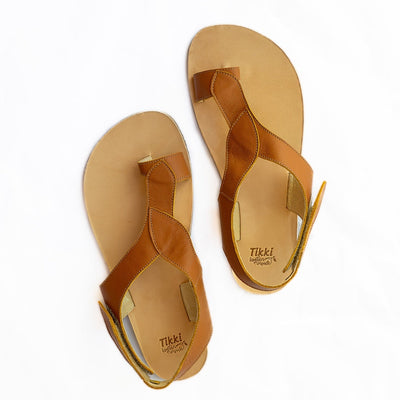 A photo of light brown Tikki Soul leather sandals with a tan sole and footbed. Three leaf-shaped straps connect starting at a toe ring, surrounding the back of the foot and coneecting to a velcro closure at the outside of the ankle. Both shoes are shown here staggered from above against a white background. #color_sahara