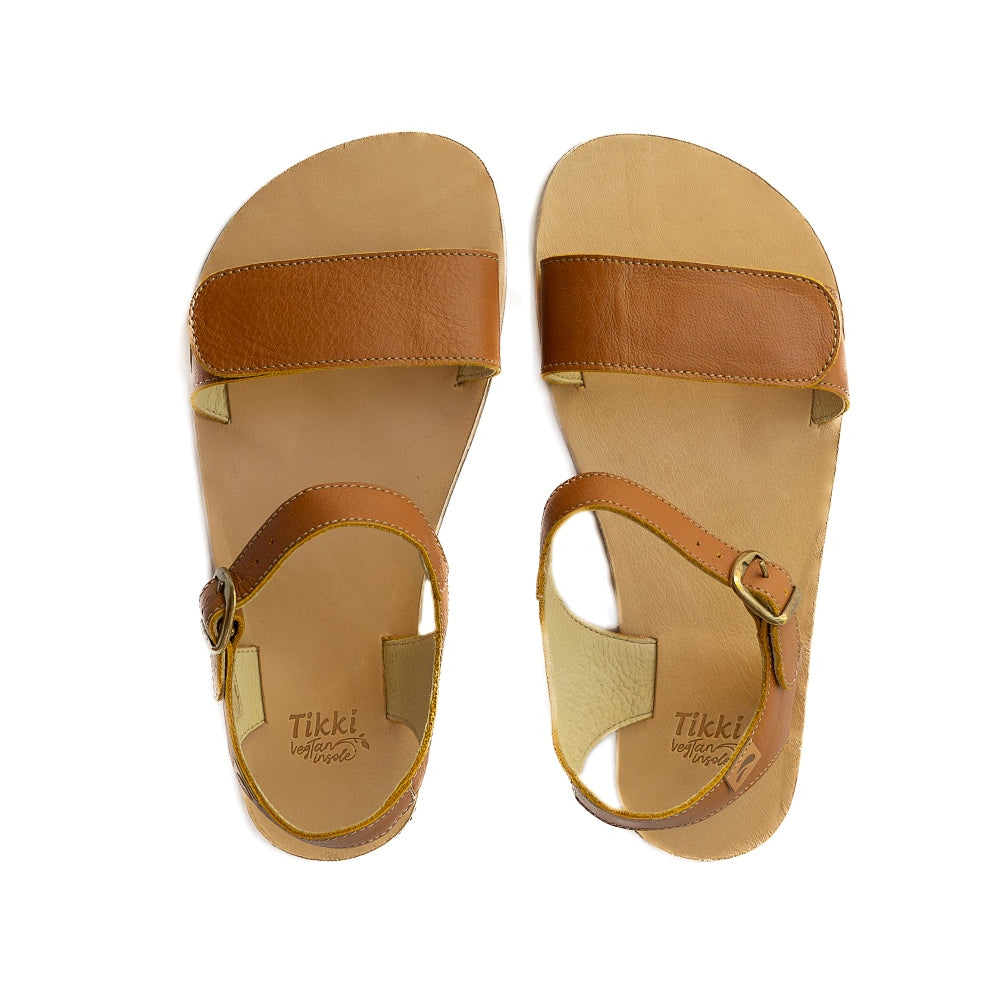 Tikki Vibe brown leather sandals with a tan footbed and soles. A thick velcro strap secures the foot at the toes with a slimmer ankle buckle-closure strap in the back. Both shoes are shown here from above against a white background. #color_cream-leather