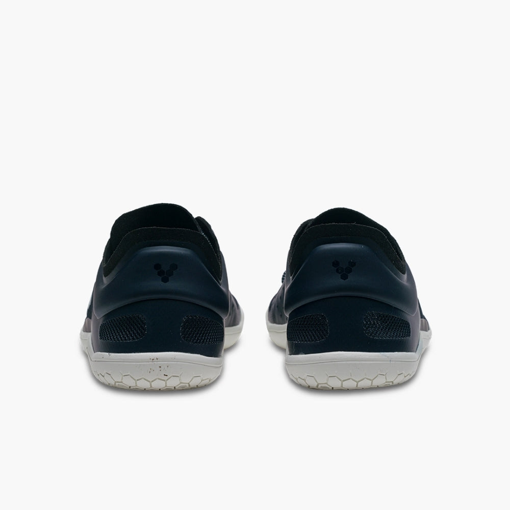 A photo of recycled plastic Navy Vivobarefoot Primus lite sneakers with white rubber soles and a white vivobarefoot logo on the side. Recycled mesh fabric surrounds the shoe with a thicker recycled guard around the sole, laces, and ankle opening. Both shoes are shown from the back against a white background. #color_navy