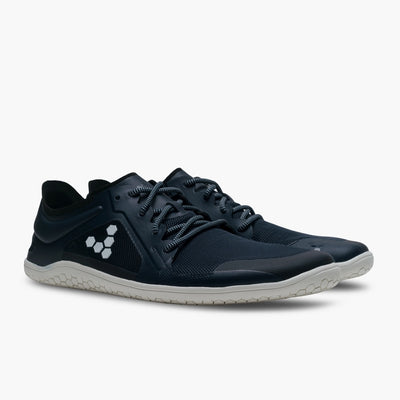 A photo of recycled plastic Navy Vivobarefoot Primus lite sneakers with white rubber soles and a white vivobarefoot logo on the side. Recycled mesh fabric surrounds the shoe with a thicker recycled guard around the sole, laces, and ankle opening. Both shoes are shown facing diagonally right against a white background. #color_navy