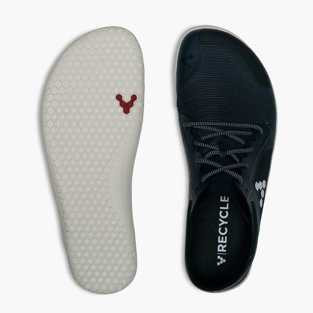 A photo of recycled plastic Navy Vivobarefoot Primus lite sneakers with white rubber soles and a white vivobarefoot logo on the side. Recycled mesh fabric surrounds the shoe with a thicker recycled guard around the sole, laces, and ankle opening. Right shoe is shown from above and left shoe sole is shown here against a white background. #color_navy