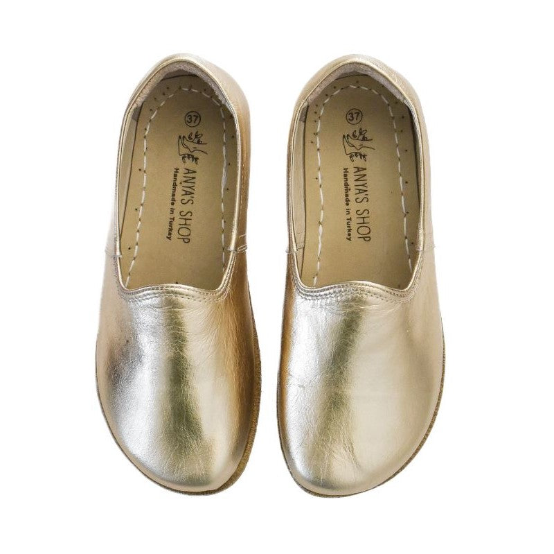 #color_goldA photo of Gold Yasemin Leather loafers Designed by Anya with a leather upper and tan rubber soles. The loafers have a small curve up on the top of the foot for design. Shoes are shown from the top down against a white background. #color_gold