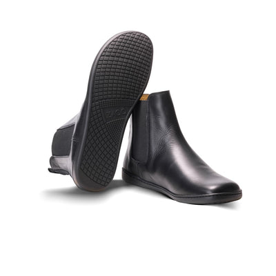 Smooth black leather Zaqq Equity unlined Chelsea boots. Lining is a camel color. A pull tab is present at the back of the boot opening. Left shoe is shown here facing diagonally to the right with the right shoe propped up next to it showcasing the sole against a white background. #color_black