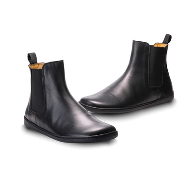 Smooth black leather Zaqq Equity unlined Chelsea boots. Lining is a camel color. A pull tab is present at the back of the boot opening. Left shoe is shown here facing diagonally to the left next to the right shoe facing diagonally right against a white background. #color_black