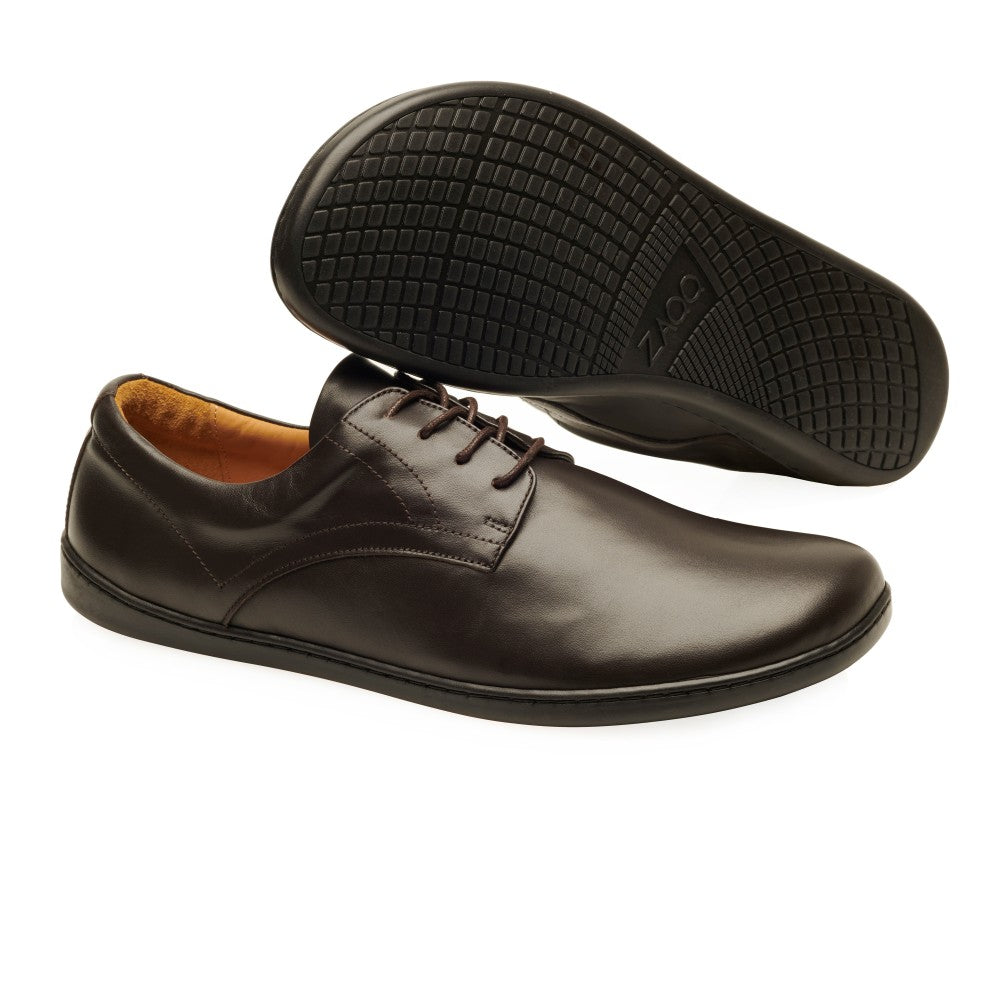 Dark Brown Zaqq Peaq leather dress shoes with dark brown laces and black rubber soles. Right shoe is shown facing right with the left shoe sole leaning on it against a white background. #color_dark-brown