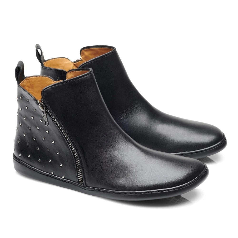 All black leather Zaqq Qlare boot with tan leather lining and a black pull tab. The front of the boot is plain while the back has small silver studs with a silver diagonal zipper on the outside ankle. Both shoes are shown facing diagonally right against a white background. #color_black