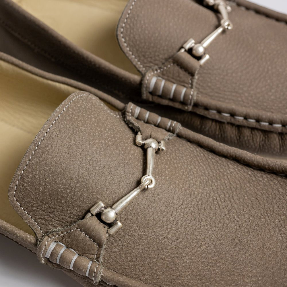 A photo of the Zeazoo Cheetah loafers made from a natural nappa leather upper on a tan Vibram sole. The loafers are stone in color and have a silver metal detail across the top of the foot. Both loafers are shown together from above on a white background with a focus on the silver metal details. #color_stone