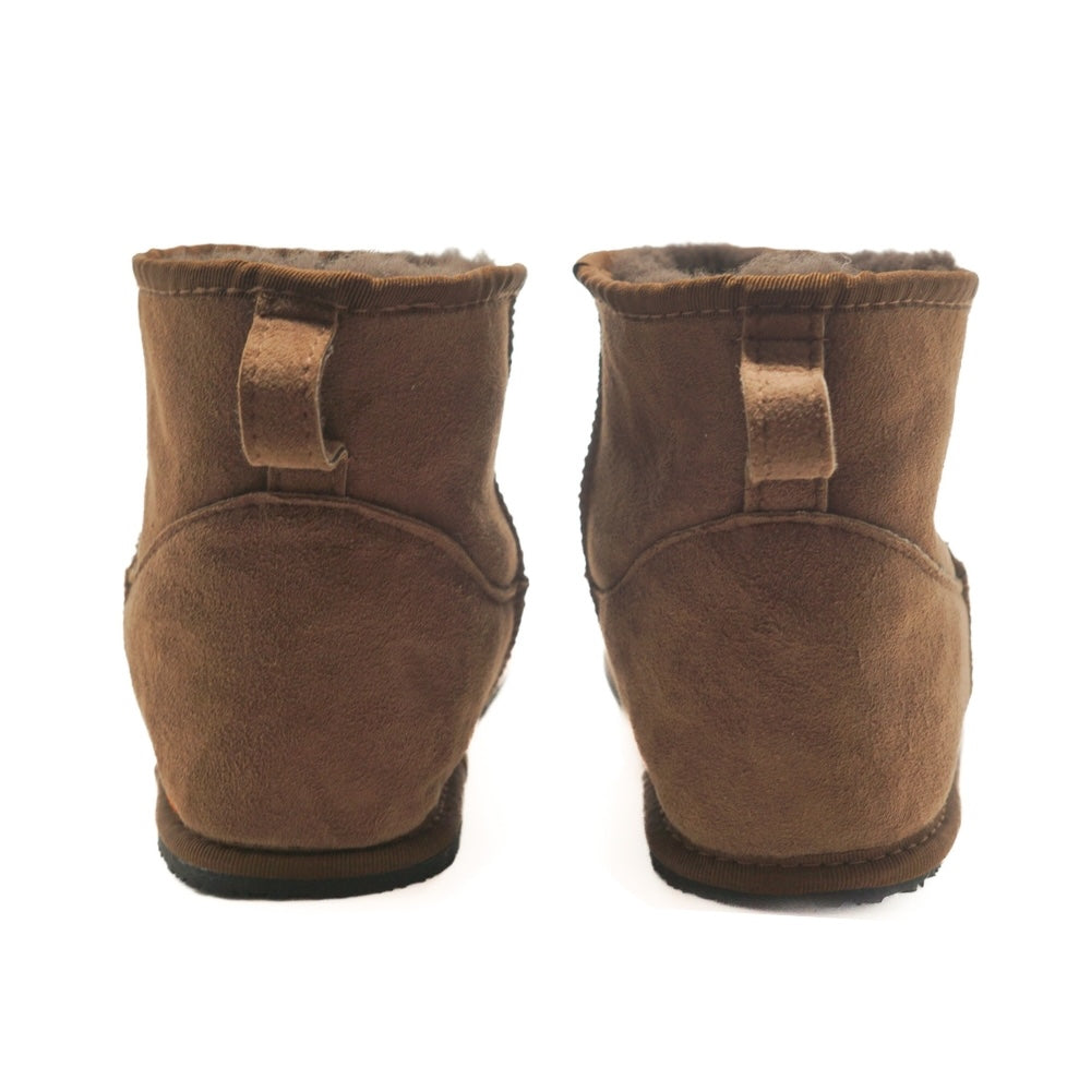 A plain brown Zeazoo Dingo Mini sheepskin ankle boot with a back pull tab, brown wool lining, and black rubber vibram soles. Both shoes are shown from the back against a white background. #color_brown