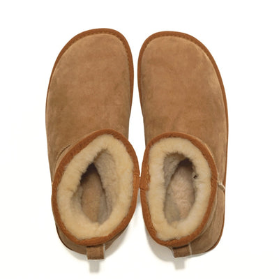 A plain light-brown Zeazoo Dingo Mini sheepskin ankle boot with a back pull tab, cream wool lining, and cream rubber vibram soles. Both shoes are shown from above against a white background. #color_chestnut